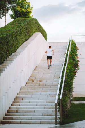 Young athlete man do morning run. Male runs up the stairs doing cardio exercisesの写真素材