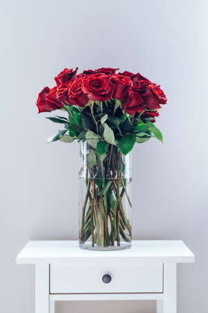 Bouquet of fresh dark red roses staying on white table on neutral backgroundの写真素材