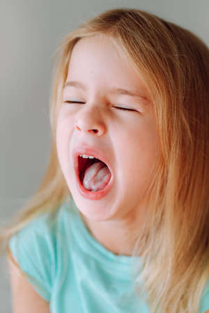Portrait of yawning little blonde girl. Lack of sleeping, high school loadの写真素材