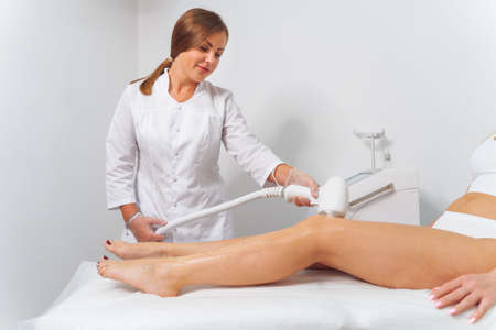 Laser epilation and cosmetology in beauty salon. Laser hair removal, skin care. Master dolaser hair remove prosedure.の写真素材