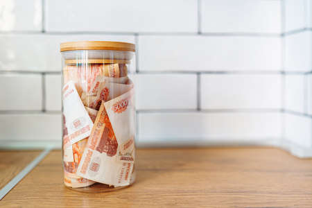 Russian banknotes of 5000 rubles packed in a glass jar on a kitchen. Business, finance concept. Saving money.の写真素材
