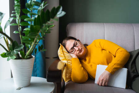 attractive blond woman slept on the sofa while reading book. High quality photoの写真素材