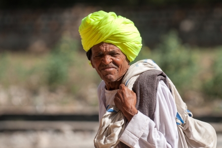 Ranthambore, India  February 4, 2011: Rajasthani man in yellow turban carries a sack in Ranthambore.  Rajasthani people are renown as the most colorful people in India.のeditorial素材