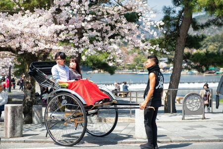 Kyoto, Japan - April 4, 2013: Tourists enjoy a pause in a pulled rickshaw in Arashiyama. Arashiyama...