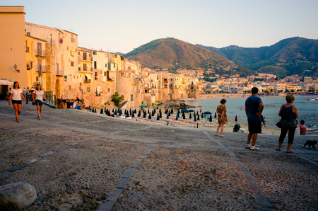 Cefalu, Sicily, Italy - July 17, 2013  Tourists enjoy the beach and the old town at sunset in Cefalu, Sicily. Cefalu is one of the most popular destinations for a Sicilian vacation のeditorial素材