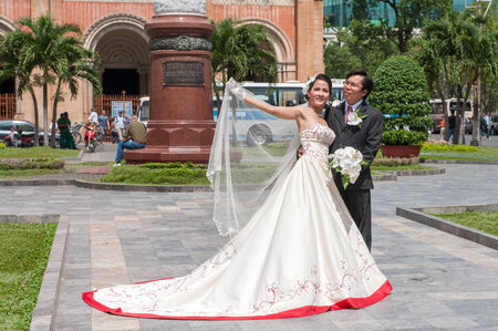 Ho Chi Minh City, Vietnam - March 5, 2009  Wedding couple posing for photographers outside Notre Dame cathedral  The brides usually change into three different gowns during the reception のeditorial素材