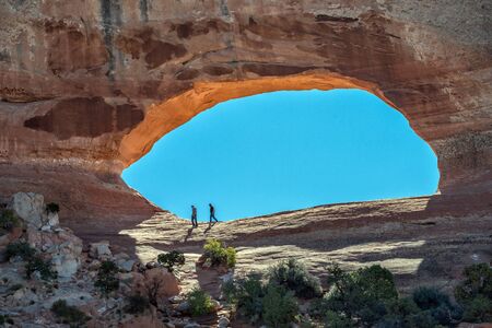 Moab, UT, USA - October 4, 2014: Two tourists explore Wilson?s Arch south of Moab and Arches National Park. Wilson?s Arch is one of many thousand arches in the Moab area.のeditorial素材