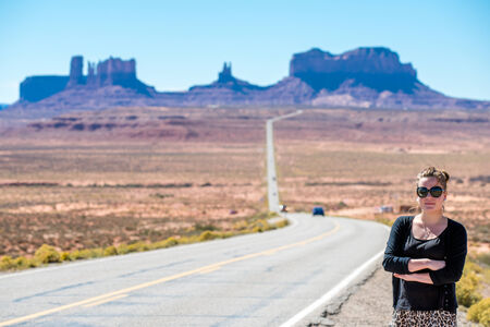 Female tourist poses at the classic route to Monument Valley from Utahの写真素材