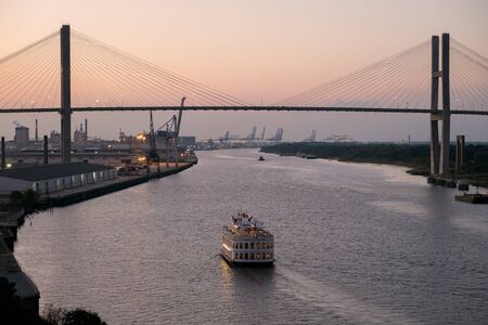 Savannah, GA, USA - October 13, 2014: Riverboat cruises at dusk on Savannah River below the Eugene Talmadge Memorial Bridge. Established in 1733 Savannah is the oldest town in Georgia.のeditorial素材