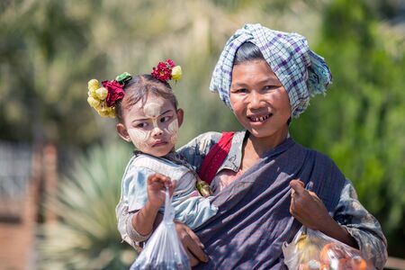 Bagan, Myanmar - February 8, 2014: Burmese betel chewing woman with child. Facial painting with white-yellow color called Thanaka is a popular cosmetic in Myanmar.のeditorial素材