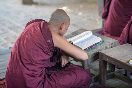 Bagan, Myanmar - February 8, 2014: Young Burmese novice monk studies a book. Buddhists in Myanmar belong mainly to the Theravada tradition.のeditorial素材