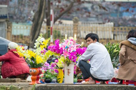 Lao Cai, Vietnam - February 15, 2015: Vietnamese man sells flowers at a street market in Lao Cai. The Lao Cai province is a major tourist destination in northern Vietnam.のeditorial素材