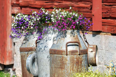 Traditional old milk containers decorated with summer flowers in the Swedish folklore district Dalecarlia.の写真素材