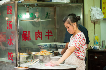 Xian China   July 3 2012: Hui muslim woman prepares street food at famous Muslim Street in Xian. Hui people are a Muslim ethnic minority in Xian and run a lively market at Muslim Street.のeditorial素材