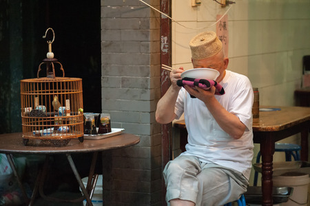 Xian China   June 20 2012: Hui man enjoys a meal at famous Muslim Street in Xian. Hui people are a Muslim ethnic minority in Xian and run a lively market at Muslim Street.のeditorial素材