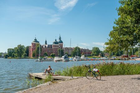 Mariefred, Sweden - August 4, 2011: People relax by Lake Malaren with Gripsholm Castle in the background during summer in idyllic small town Mariefred. This historic town on Lake Malaren is a popular tourist destination.のeditorial素材