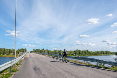 Unrecognizable biker crossing the border bridge between Sweden and Finland at Muonio river in northern Scandinaviaの写真素材
