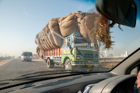 Rajasthan, India - February 3, 2011: Overloaded truck on a country road in Rajasthan. Trucks carrying heavy loads characterize traffic in India.のeditorial素材