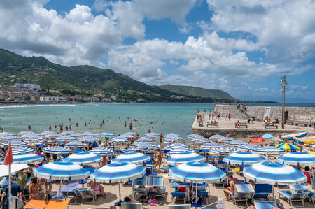 CefalÃ¹, Italy - July 2, 2023: Tourists enjoy the beach in CefalÃ¹ on a sunny day in July. Historic CefalÃ¹ is a major tourist destination on Sicily.のeditorial素材