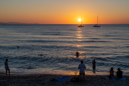 CefalÃ¹, Italy - July 5, 2023: Tourists enjoy sunset at the beach in CefalÃ¹. Historic CefalÃ¹ is a major tourist destination on Sicily.のeditorial素材