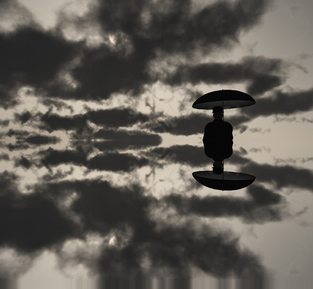 Man with umbrella in clouds. Black and white picture.の写真素材