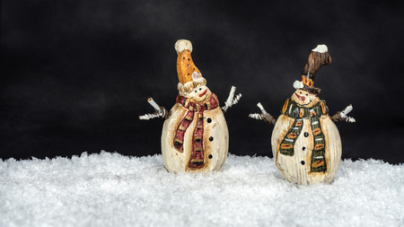 Merry Christmas: Pair of two smiling traditional vintage snowmen dolls in festive Christmas decoration and white snow landscape isolated on dark background for text - concept decoration ornamentの写真素材