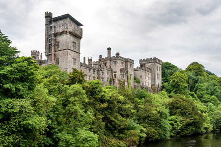 Ireland, Lismore: Fornt view of famous Irish Lismore Castle with trees, river and bad weather with grey cloudy sky in the background. June 12, 2015のeditorial素材