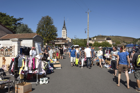 France, Crus des Beaujolais, Fleurie: People citizens tourists men women visit the local French flee market yard sale with church, dealer stalls and clear blue sky in the background. August 06, 2017のeditorial素材