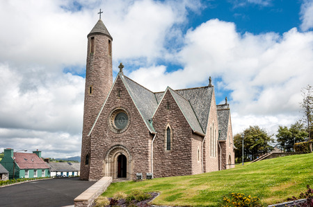 Ireland, Donegal: Typical street scene with main entrance area of Irish St. Patrick's Church, park, round tower, cross and blue cloudy sky in the background. June 21, 2015のeditorial素材