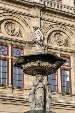 Austria, Vienna, Opernring: Side view of famous Vienna State Opera (Wiener Staatsoper) facade with sculpture on fountain in the city center of the Austrian capital and blue sky - concept culture artのeditorial素材