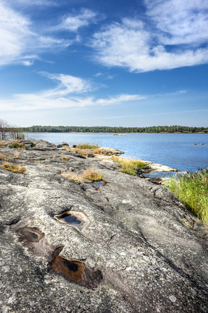 Sweden, Baltic Sea: Beautiful coastline coastal scene with nature, environment, calm water, riverside rocks at rocks, clouds and blue sky in the background - concept vacation travel relaxation.の写真素材