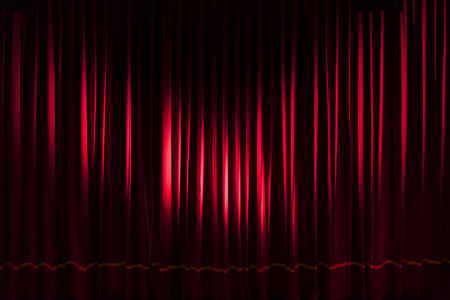 Heavy red curtain illuminated by two spotlights - concept theater show entertainment performance backgroundの写真素材