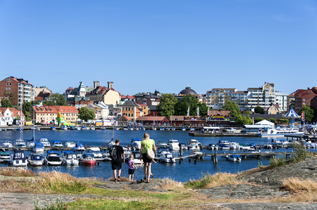 Sweden, Karlskrona, Stakholmen: Panoramic view of Swedish town with young family, central marina, water, boats, pier and buildings at Baltic Sea. July 07, 2014のeditorial素材