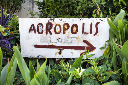 Greece, Athens, Anafiotika: Hand painted sign indicating direction to the famous Acropolis in the city center of the Greek capital - against sunlightの写真素材