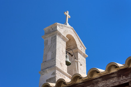 Steeple with bronze tower bell and cross on top of old small church chapel with blue sky in the background - concept Christianity religion god faith tradition architecture history sign Jesus Christの写真素材