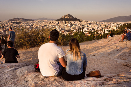 Greece, Athens, Lycabettos: Sunset panorama view of famous Mount Lycabettus in the city center of the Greek capital with people young couple woman man skyline horizon and blue sky. April 25, 2018のeditorial素材