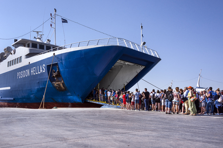 Greece, Aegina: People residents tourists men women enter a big ferry at the port of famous Greek island with skyline, boats, ferries and blue sky - concept travel transport leisure. April 28, 2018のeditorial素材
