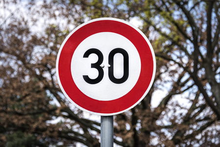 Germany: German traffic sign with speed limit 30 kilometers - concept traffic velocity speed rate limitation warning information rule law prohibition street roadの写真素材