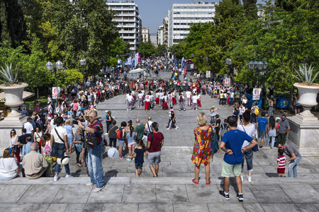 Greece, Athens: Famous Syntagma square with central water fountain, people, residents, women, men, park, green trees in the city center of the Greek capital and blue sky in background. April 29, 2018のeditorial素材