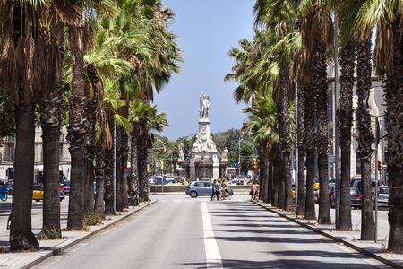 Spain, Barcelona: Street scene with green palm trees, people, cars, traffic and and famous sculpture Font del Geni Catala in the central city center of the Spanish town with blue sky. July 01, 2018のeditorial素材
