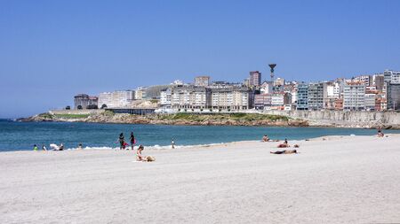 Spain, Galicia, La Coruna, A Corunna: White beach near the city center of the Spanish town with skyline, ocean water, people, tourists, swimmers and blue sky - concept summer vacation. July 13, 2018のeditorial素材