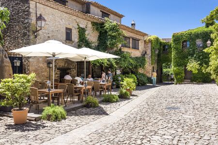 Spain, Catalonia, Peratallada: People tourists residents in a restaurant near famous Castle of Peratallada in the center of the small fortified medieval Spanish town with blue sky. June 30, 2018のeditorial素材