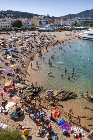 Spain, Catalonia, Costa Brava, Tossa de Mar: Famous beach of the old Spanish town with people, tourists, men, women, coastline, sea and blue sky in the background - concept mass tourism. June 30, 2018のeditorial素材