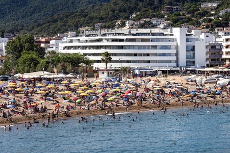 Spain, Catalonia, Costa Brava, Tossa de Mar: Famous beach of the old Spanish town with people, tourists, men, women, hotels, sea and blue sky in the background - concept mass tourism. June 30, 2018のeditorial素材