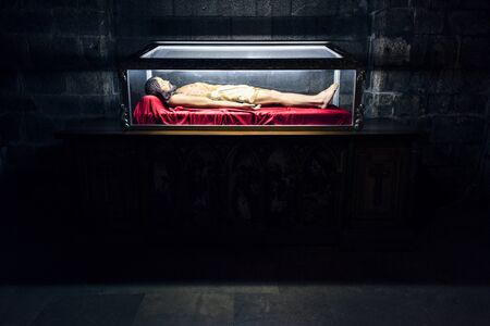 Spain, Figueres, near Dali Theatre and Museum: Lying religious figure in an illuminated shrine sarcophagus of famous Iglesia de San Pedro - St. Peter's church in the city center. Juliy 27, 2018のeditorial素材