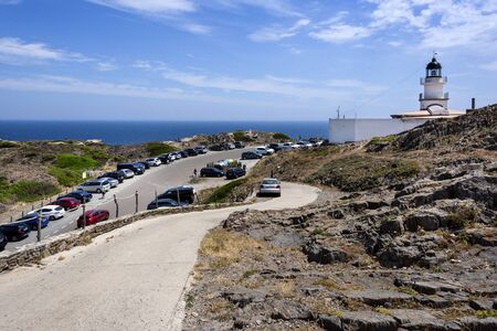 Spain, Catalonia, Cap de Creus: Panorama view of famous Spanish tourist destination with white lighthouse, parking area, blue sea water, horizon and cloudy sky - concept destination. June 28, 2018のeditorial素材