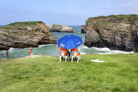 Spain, Galicia, near Ribadeo: Panorama view with lifeguard station at the famous beautiful Beach of Cathedrals (Playa de las Catedrales) at high tide with cliffs, ocean, skyline. July 15, 2018のeditorial素材