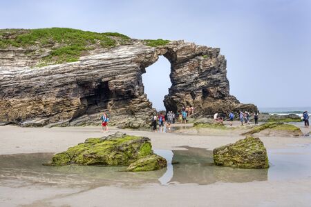 Spain, Galicia, near Ribadeo: Panorama view with people tourists residents visit the famous beautiful Beach of Cathedrals (Playa de las Catedrales) at low tide with cliffs and ocean. July 15, 2018のeditorial素材