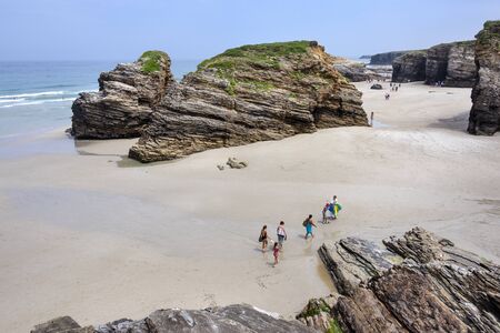 Spain, Galicia, near Ribadeo: Panorama view with people tourists residents visit the famous beautiful Beach of Cathedrals (Playa de las Catedrales) at low tide with cliffs and ocean. July 15, 2018のeditorial素材