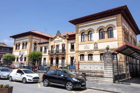 Spain, Asturias, Villaviciosa: Street scene with old refurbished school building in the city center with cars and blue sky. The Spanish town is known as capital of cider production. July 16, 2018のeditorial素材